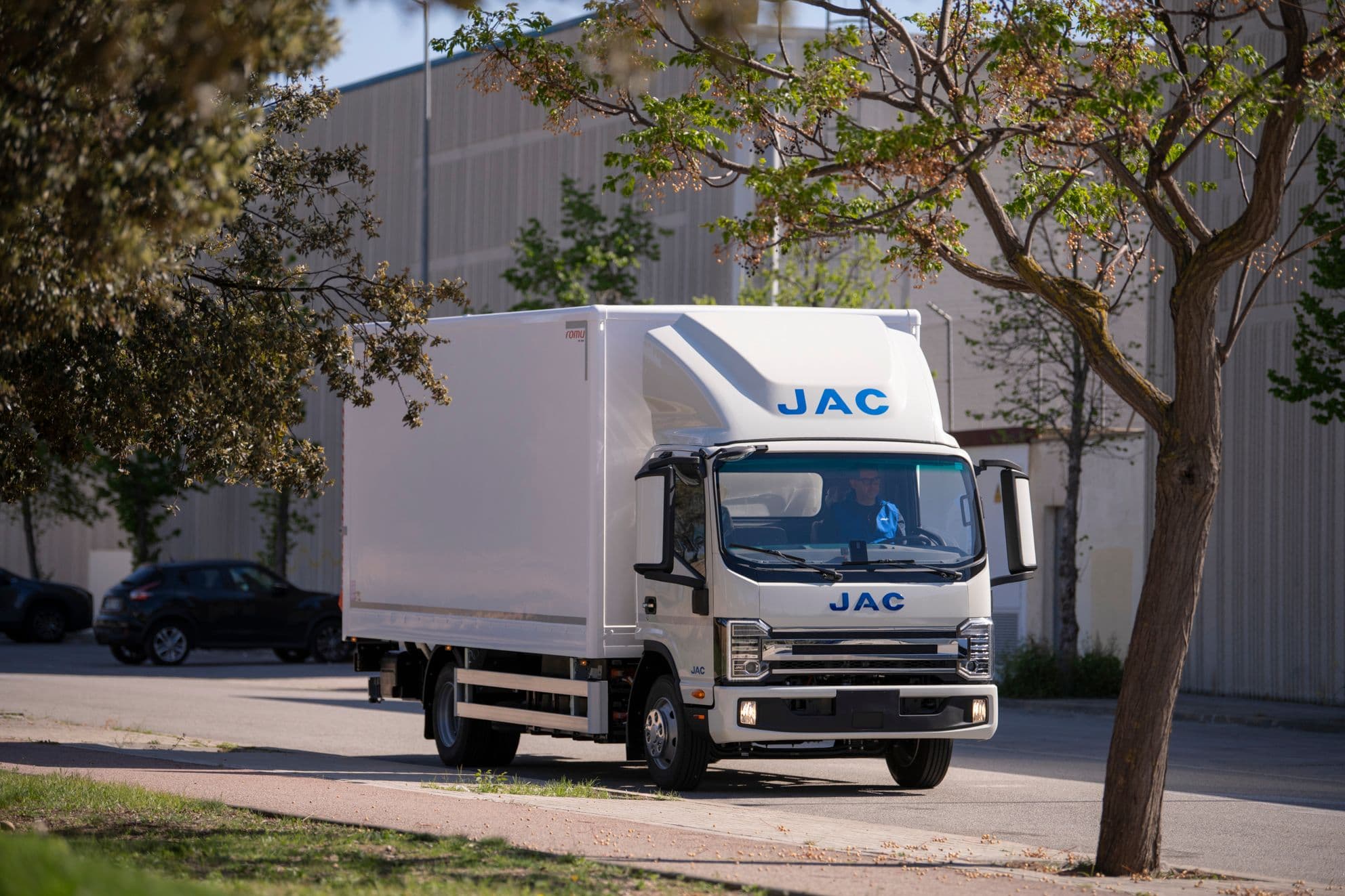 Camión blanco de la marca JAC Motors circulando por una zona industrial 