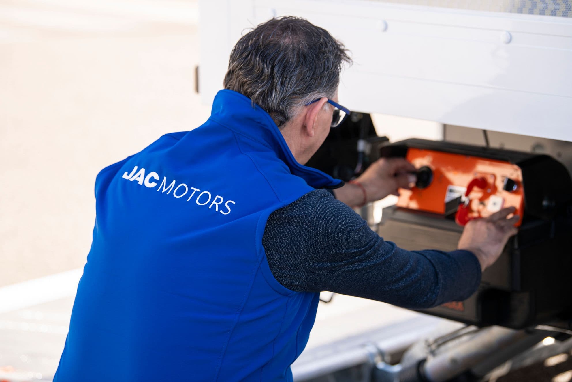 Técnico de JAC Motors realizando tareas de mantenimiento e inspección en un camión eléctrico de flota.